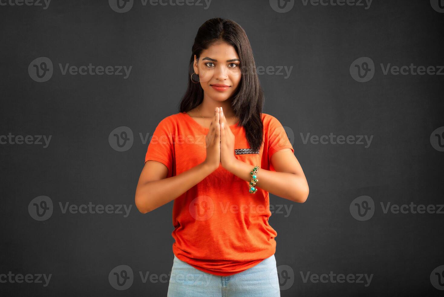 Beautiful Indian girl with welcome expression or inviting or greeting Namaste on a grey background. photo