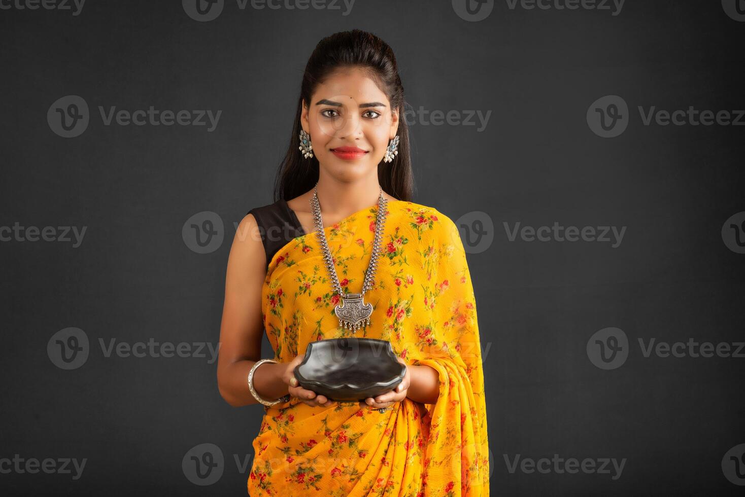 Young girl holding and posing with kitchen utensils on a grey background photo