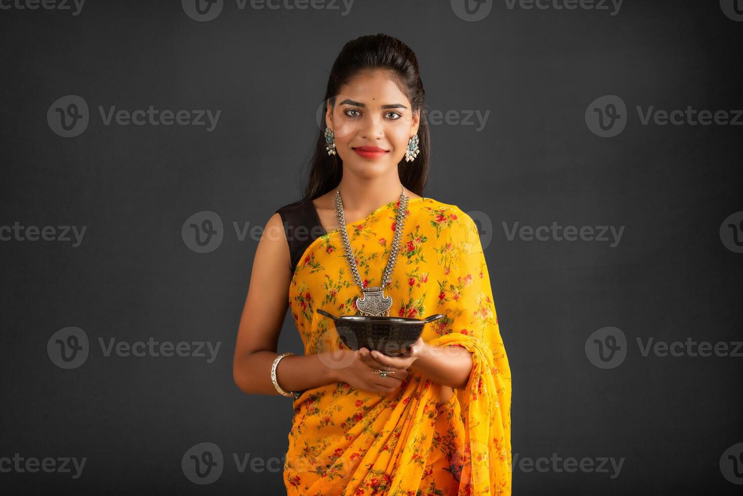 Young girl holding and posing with kitchen utensils on a grey background photo