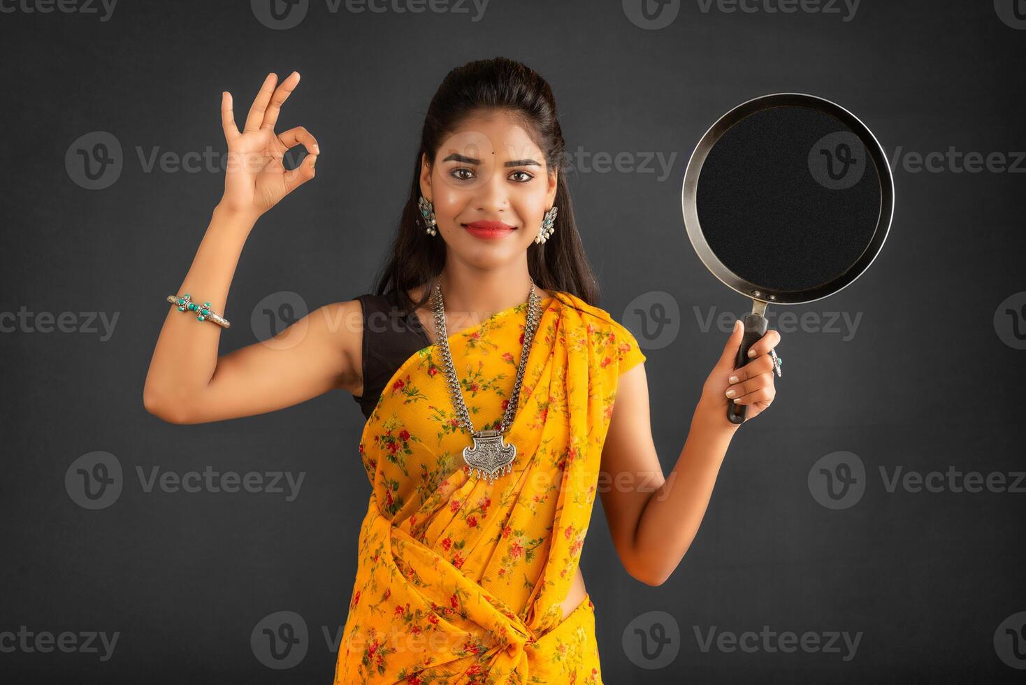 Young girl holding and posing with kitchen utensils pan on a grey background photo