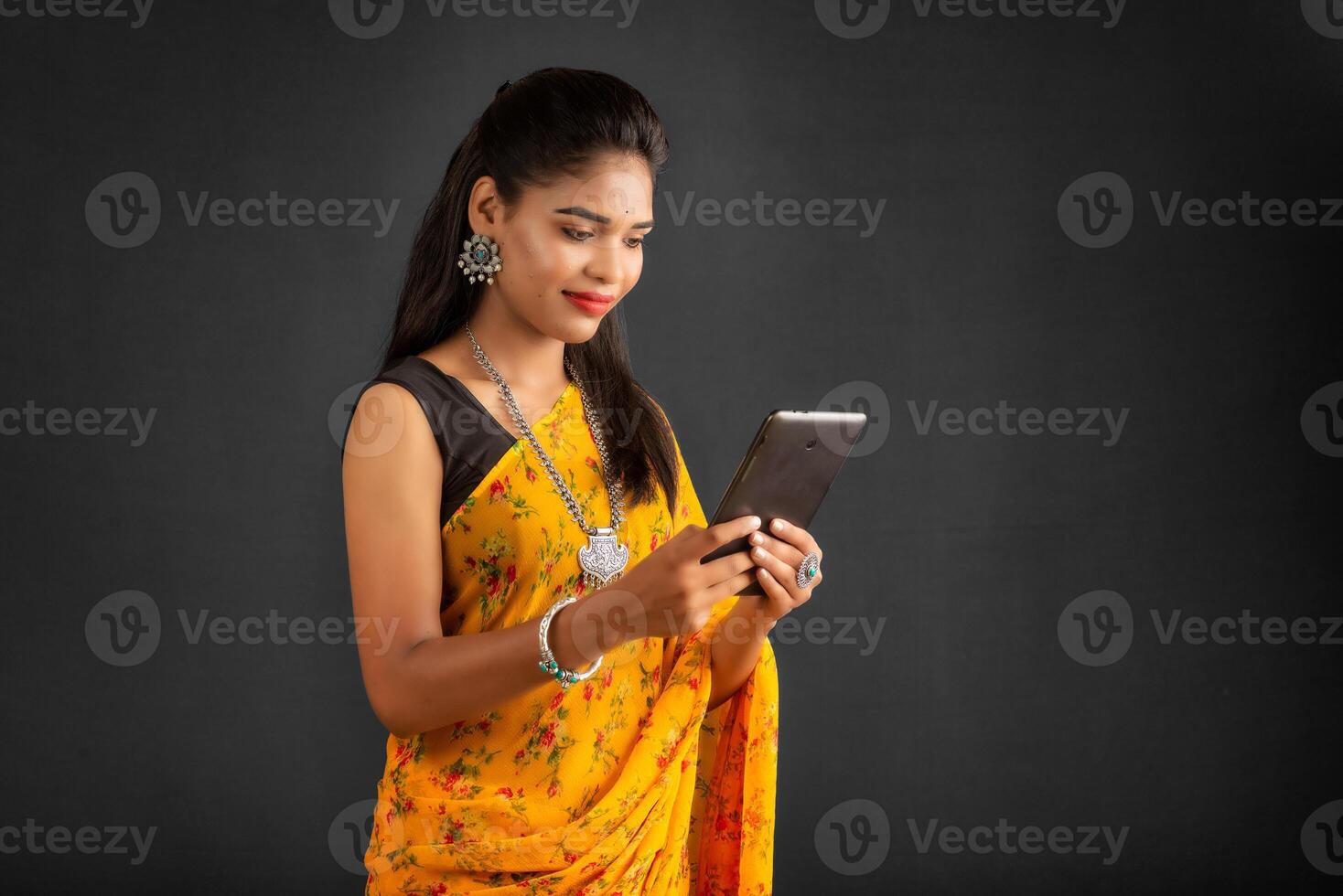 Young beautiful girl or woman holding and using smartphone or mobile or tablet phone on a grey background photo