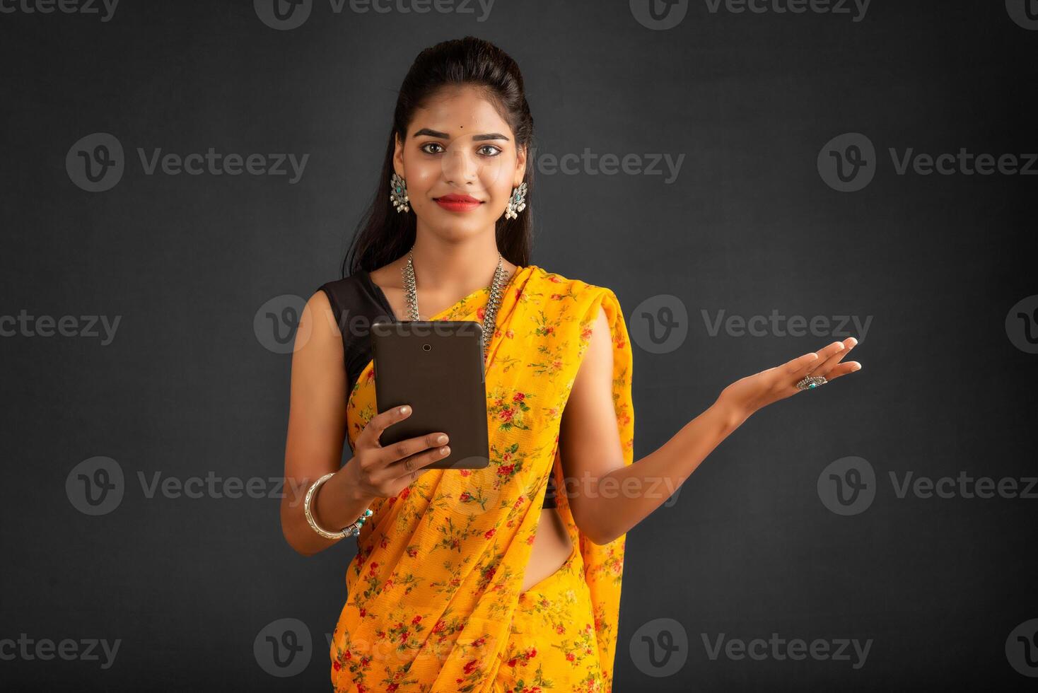 Young beautiful girl or woman holding and using smartphone or mobile or tablet phone on a grey background photo