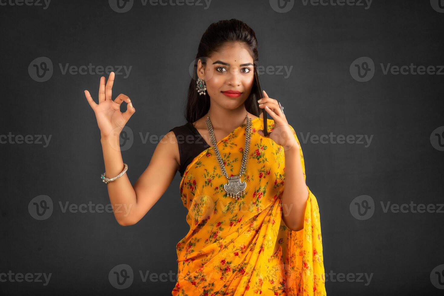 Young beautiful girl or woman holding and using smartphone or mobile or tablet phone on a grey background photo