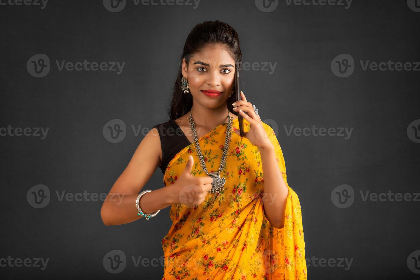Young beautiful girl or woman holding and using smartphone or mobile or tablet phone on a grey background photo