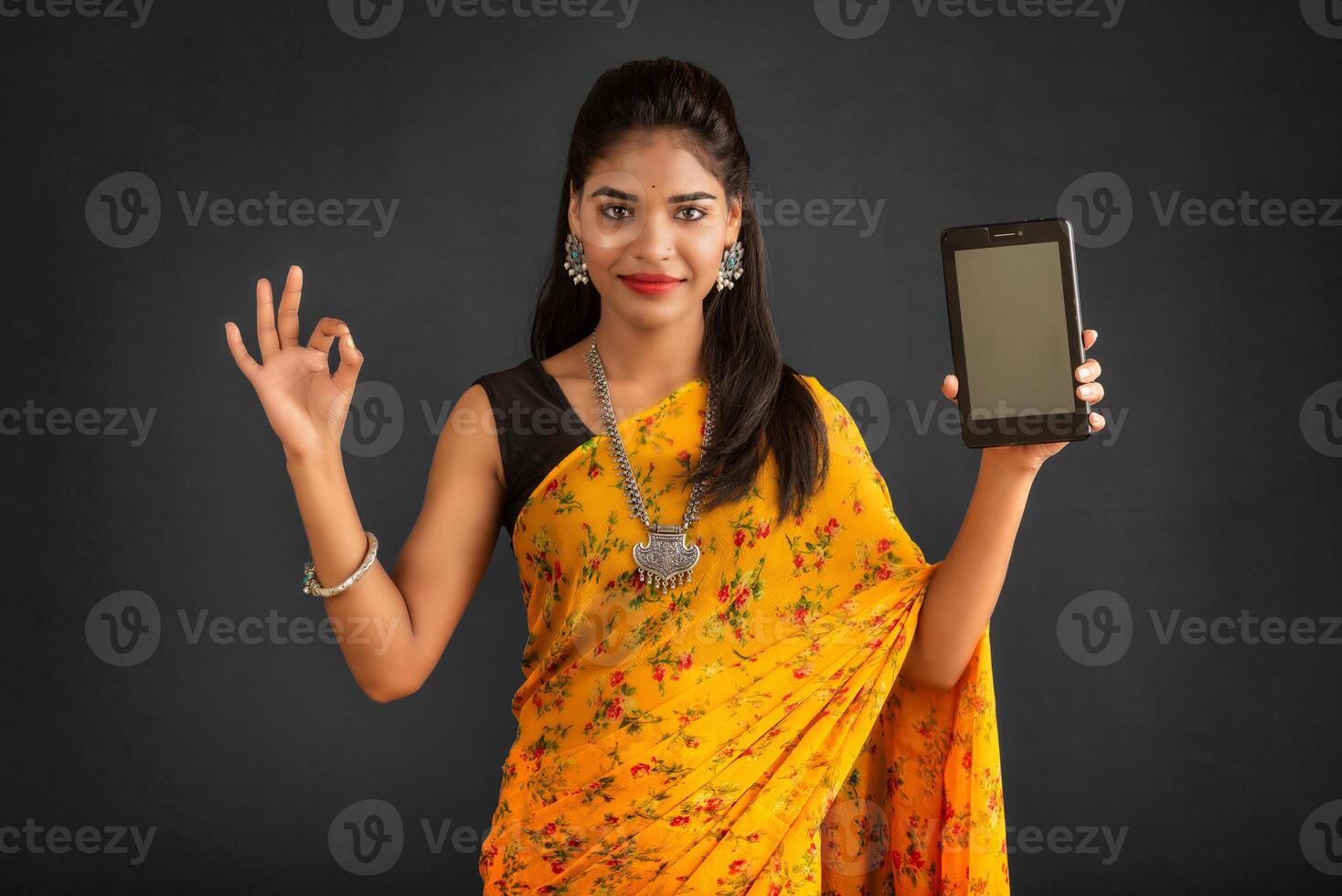 Young beautiful girl showing a blank screen of a smartphone or mobile or tablet phone photo
