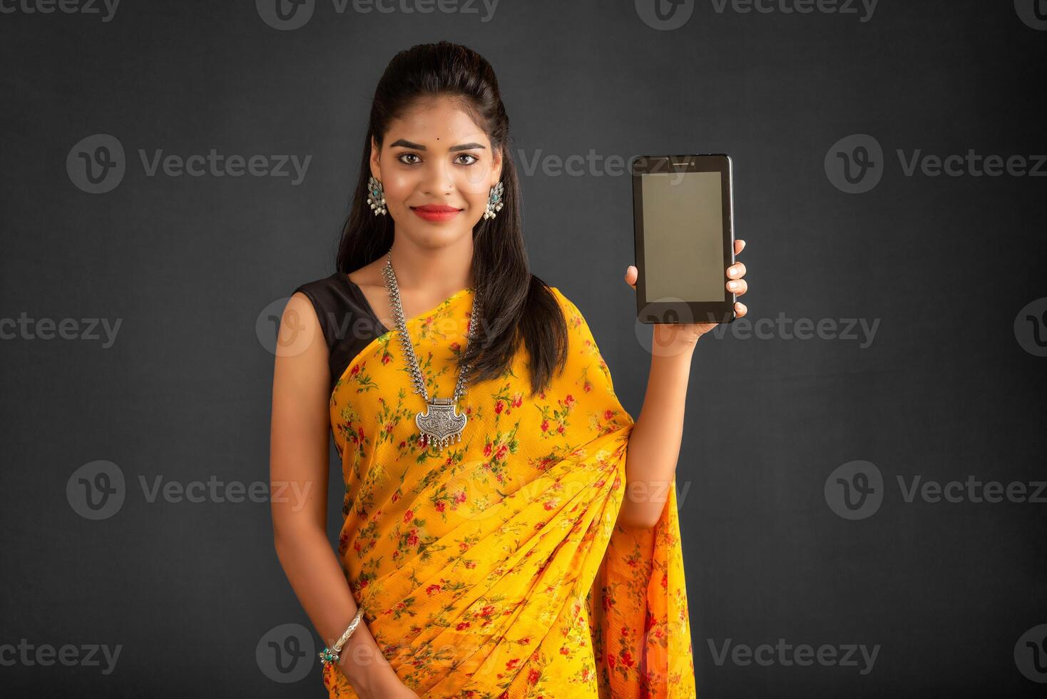 Young beautiful girl showing a blank screen of a smartphone or mobile or tablet phone photo