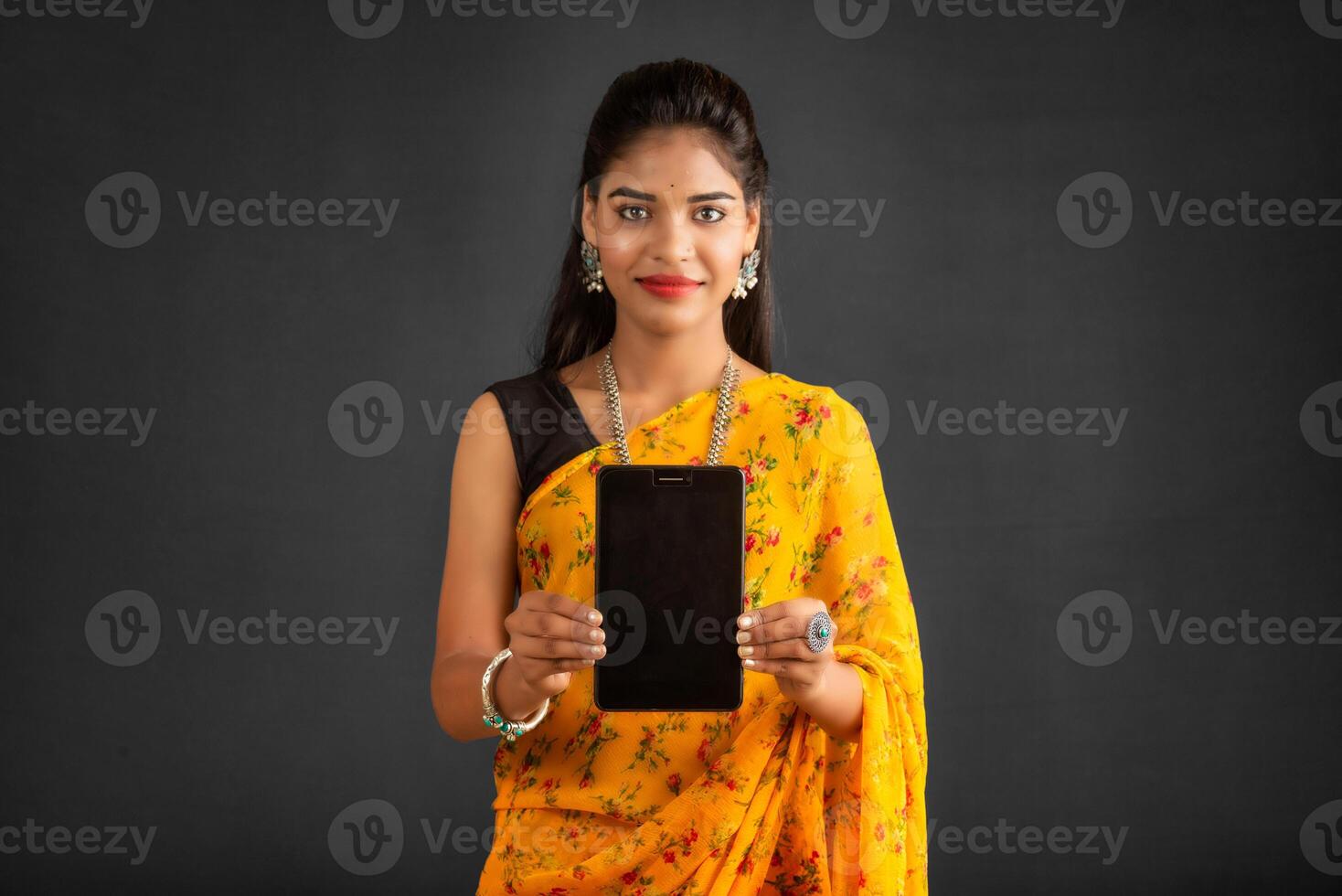 Young beautiful girl showing a blank screen of a smartphone or mobile or tablet phone photo