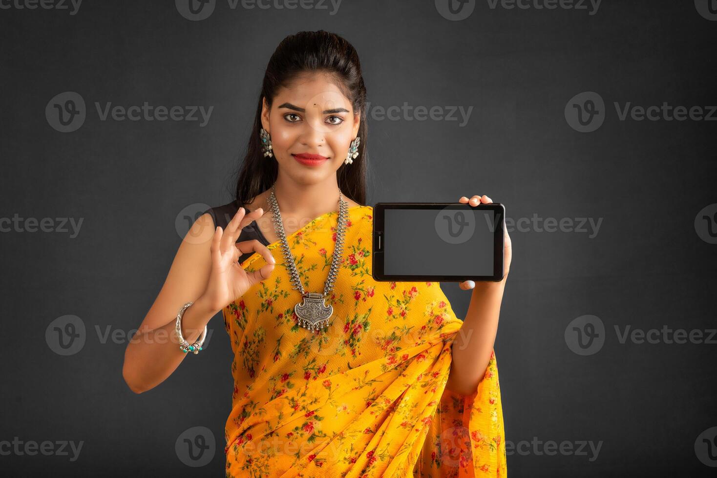 Young beautiful girl showing a blank screen of a smartphone or mobile or tablet phone photo