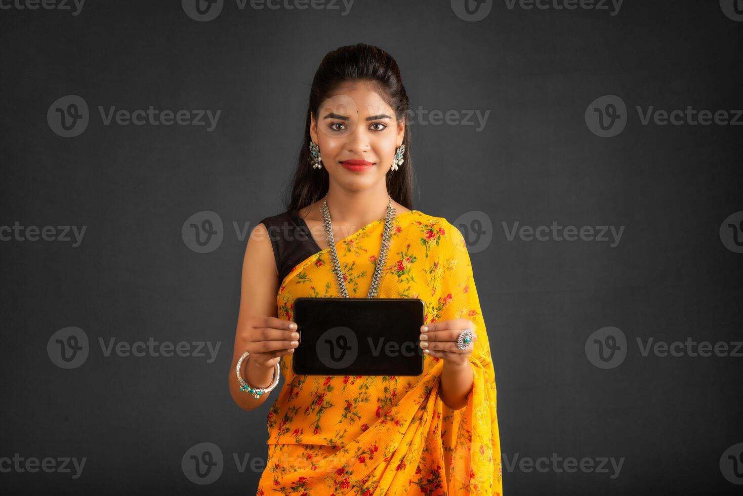 Young beautiful girl showing a blank screen of a smartphone or mobile or tablet phone photo