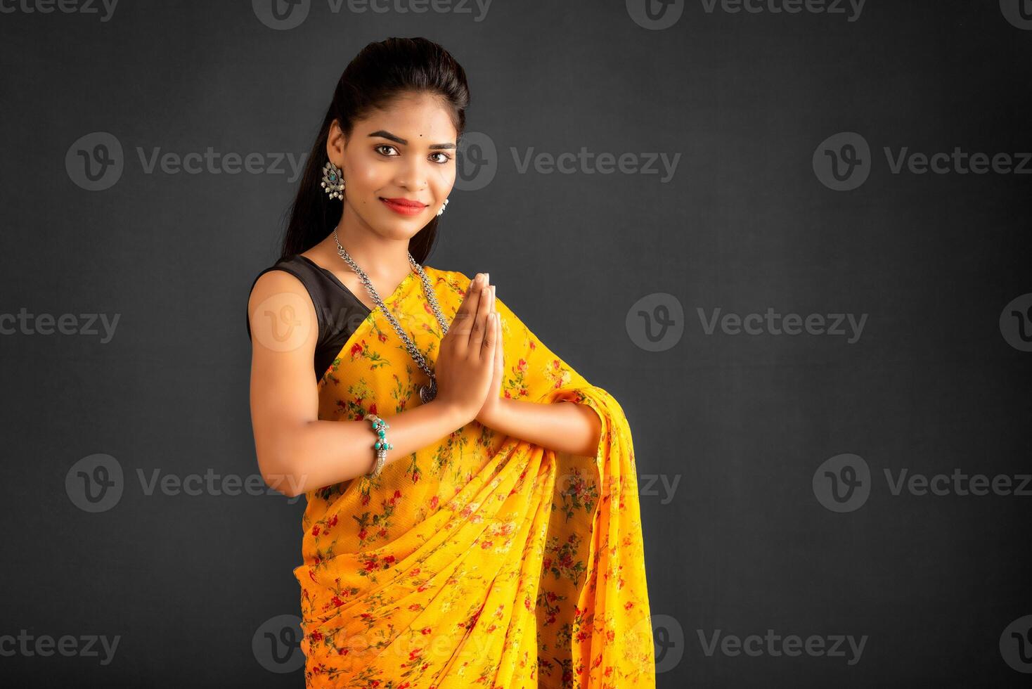 Portrait of a beautiful Indian girl in a greeting pose to Namaste hands. Indian woman in traditional saree. photo
