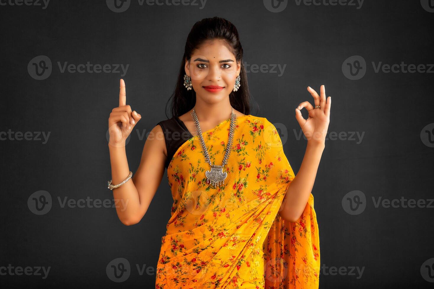 Portrait of a successful cheerful young girl pointing and presenting something with hand or finger with a happy smiling face. photo