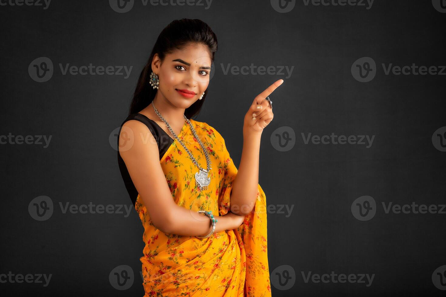 Portrait of a successful cheerful young girl pointing and presenting something with hand or finger with a happy smiling face. photo