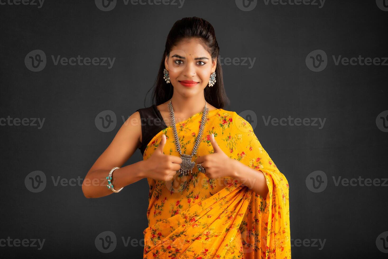 Young smiling girl showing ok sign or thumbs up on a grey background photo