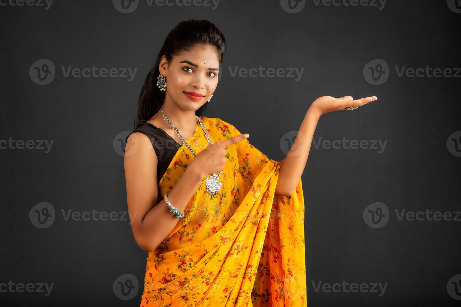 Portrait of a successful cheerful young girl holding and presenting something on hand with a happy smiling face. photo