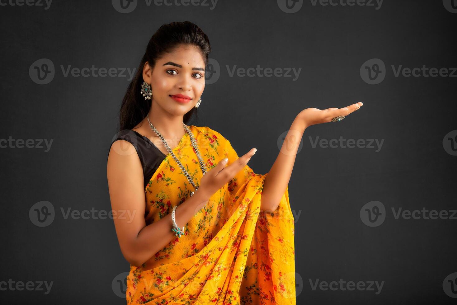 Portrait of a successful cheerful young girl holding and presenting something on hand with a happy smiling face. photo