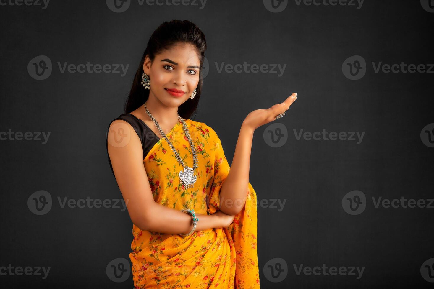 Portrait of a successful cheerful young girl holding and presenting something on hand with a happy smiling face. photo
