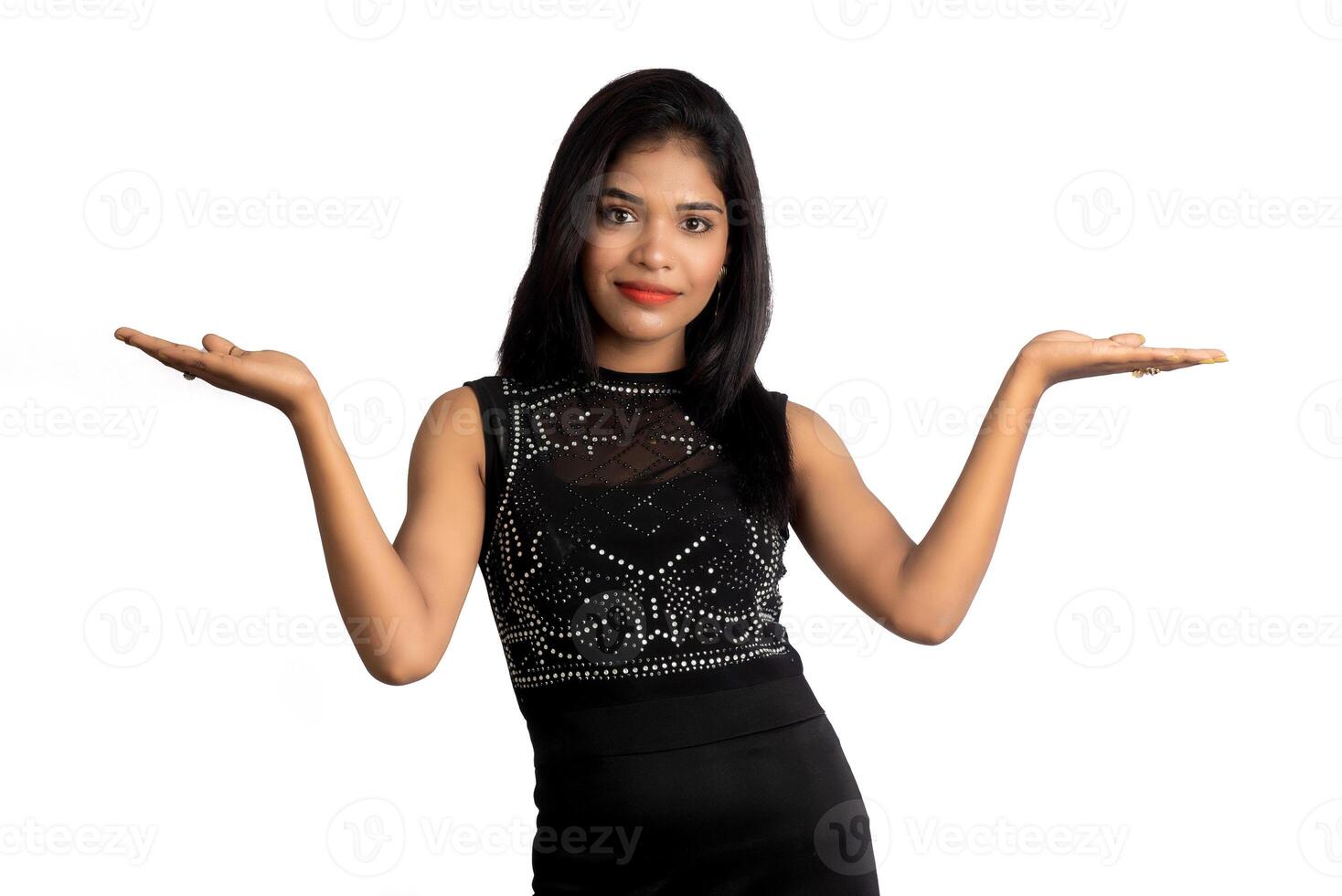 Portrait of a successful cheerful young girl pointing and presenting something with hand or finger with a happy smiling face. photo