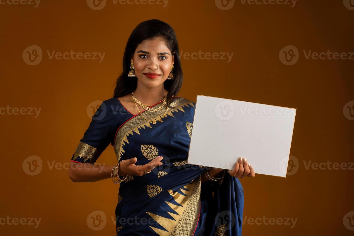 A young Indian girl or woman holding a signboard in her hands on a brown background. photo