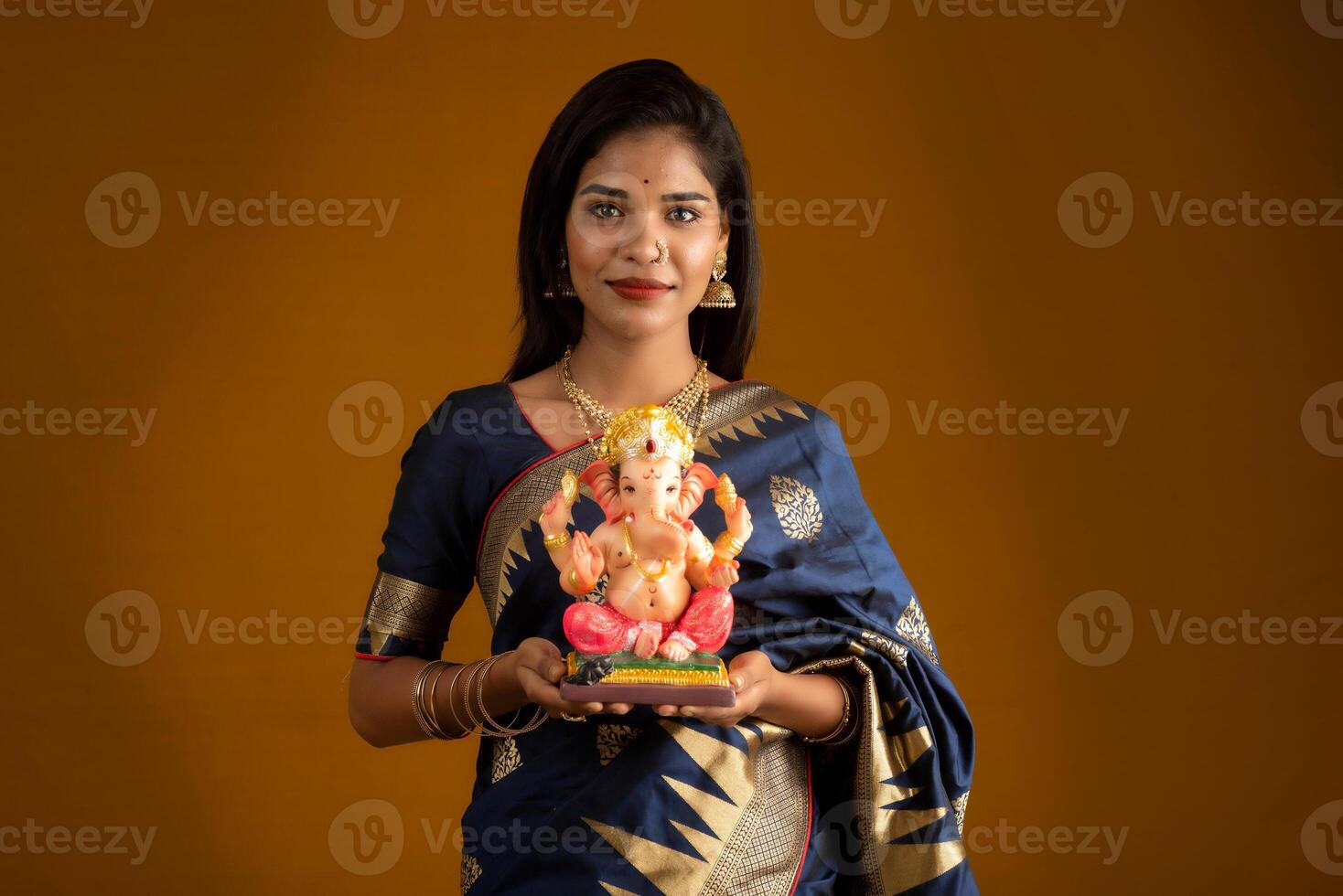 Happy young Indian woman posing with Ganesha statue on the occasion of Ganesh Festival photo