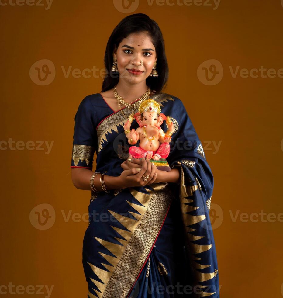 Happy young Indian woman posing with Ganesha statue on the occasion of Ganesh Festival photo