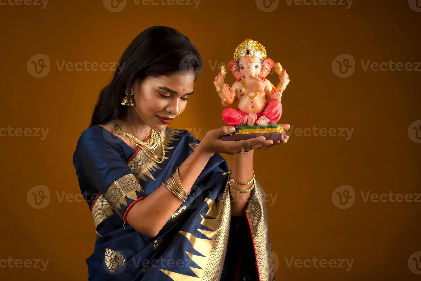 Happy young Indian woman posing with Ganesha statue on the occasion of Ganesh Festival photo