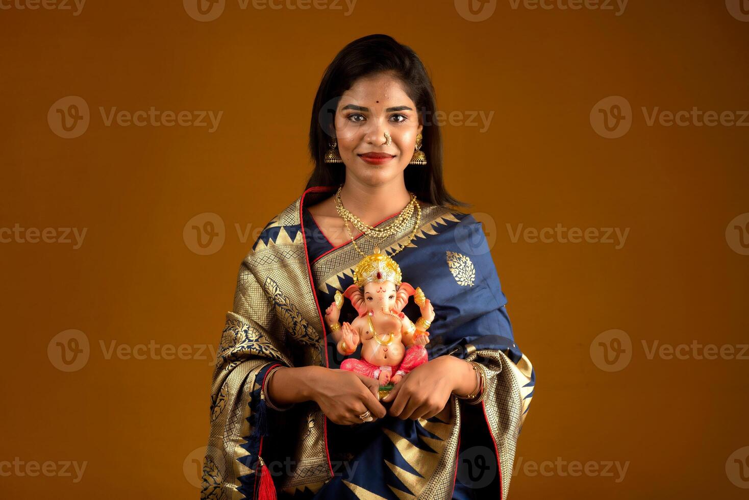 Happy young Indian woman posing with Ganesha statue on the occasion of Ganesh Festival photo