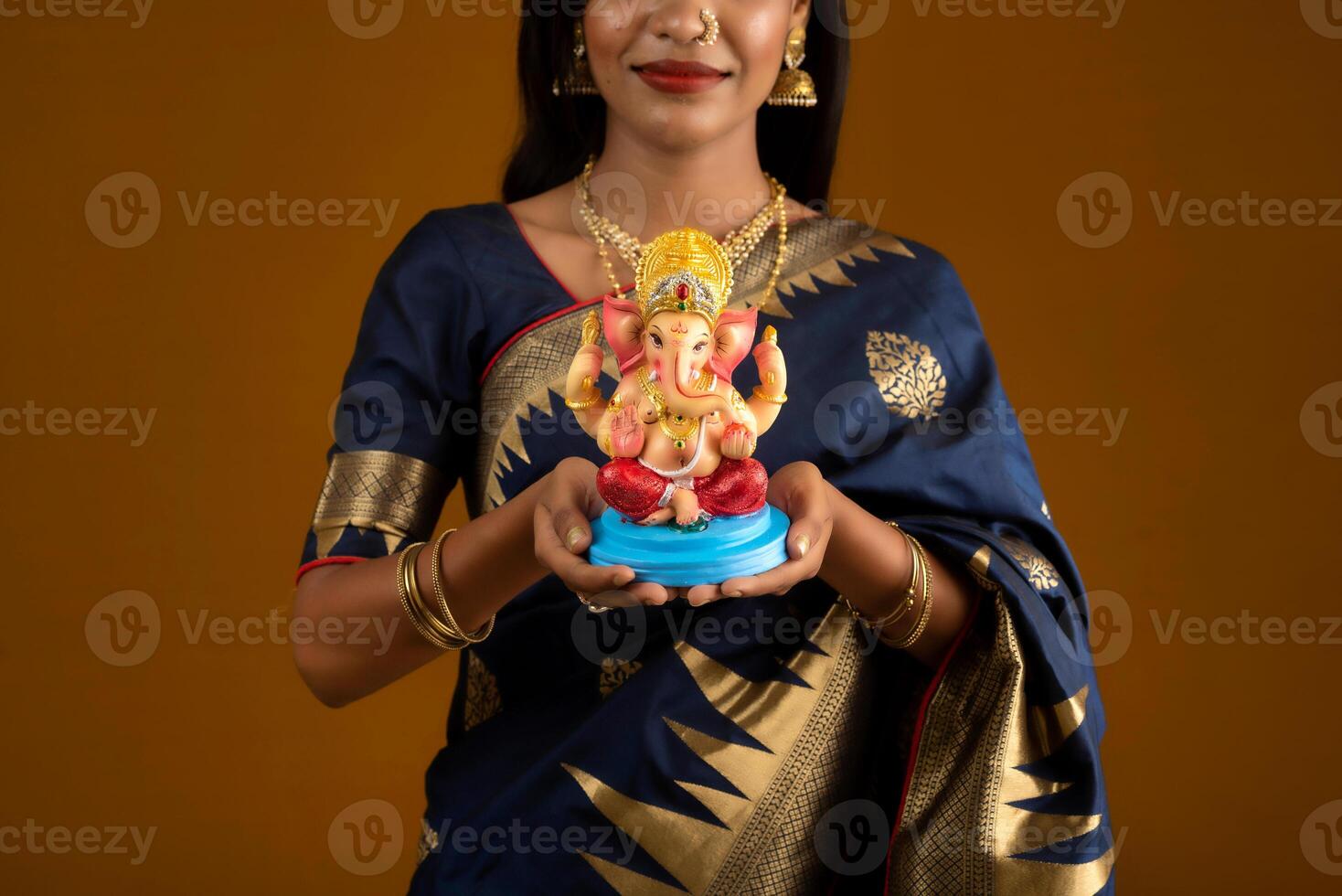 Happy young Indian woman posing with Ganesha statue on the occasion of Ganesh Festival photo
