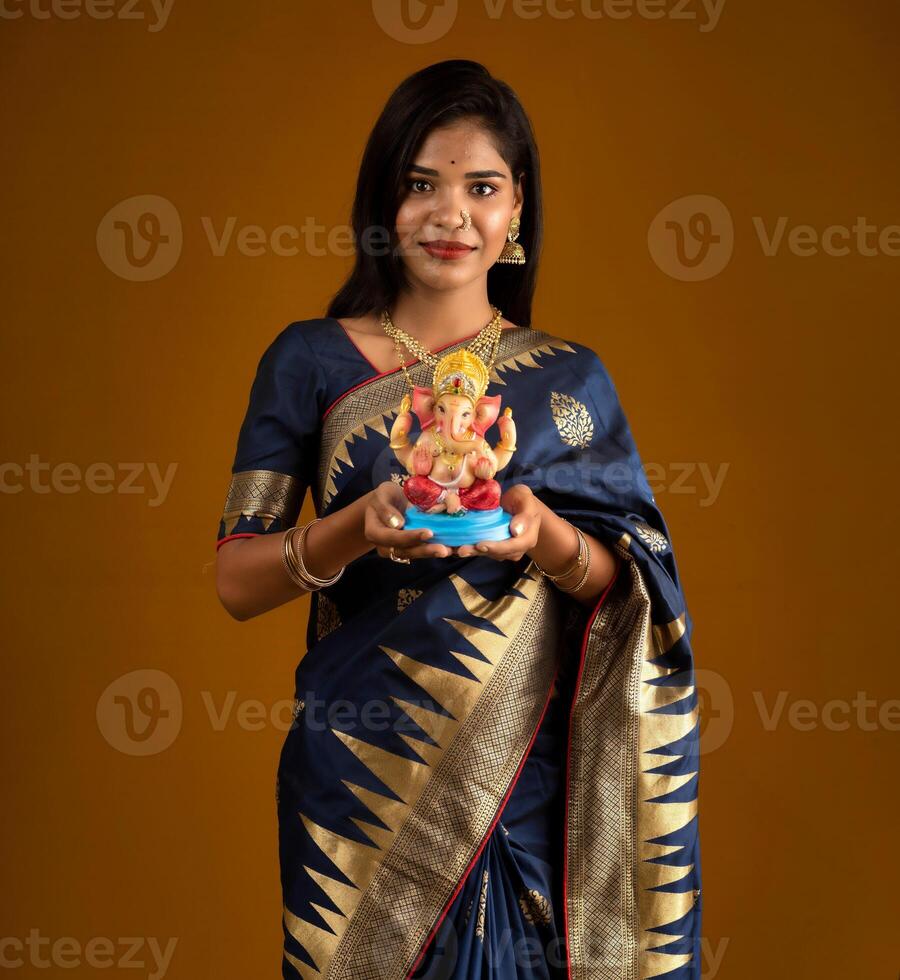 Happy young Indian woman posing with Ganesha statue on the occasion of Ganesh Festival photo