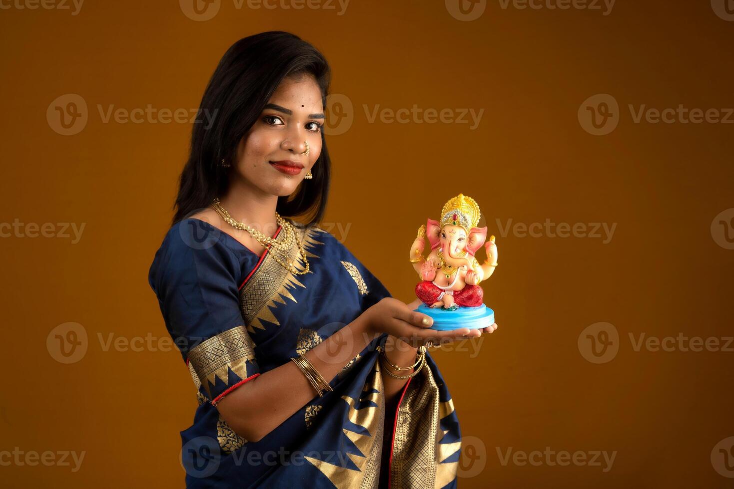 Happy young Indian woman posing with Ganesha statue on the occasion of Ganesh Festival photo