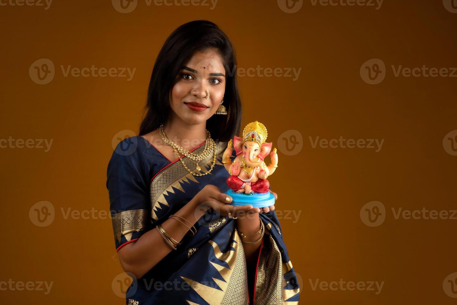 Happy young Indian woman posing with Ganesha statue on the occasion of Ganesh Festival photo
