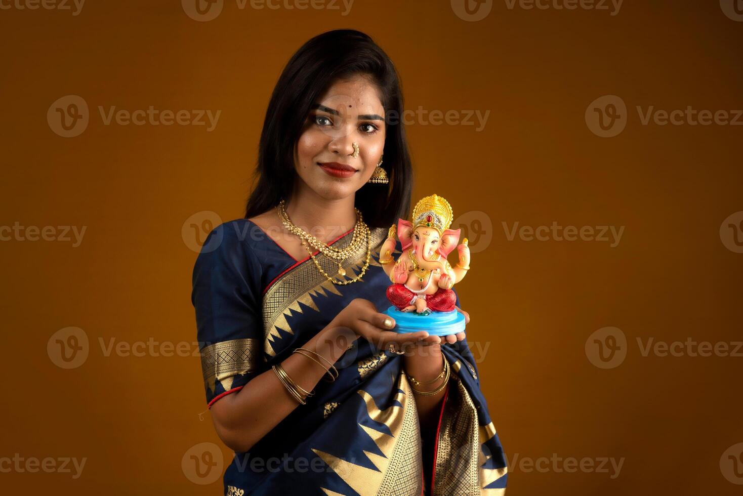 Happy young Indian woman posing with Ganesha statue on the occasion of Ganesh Festival photo