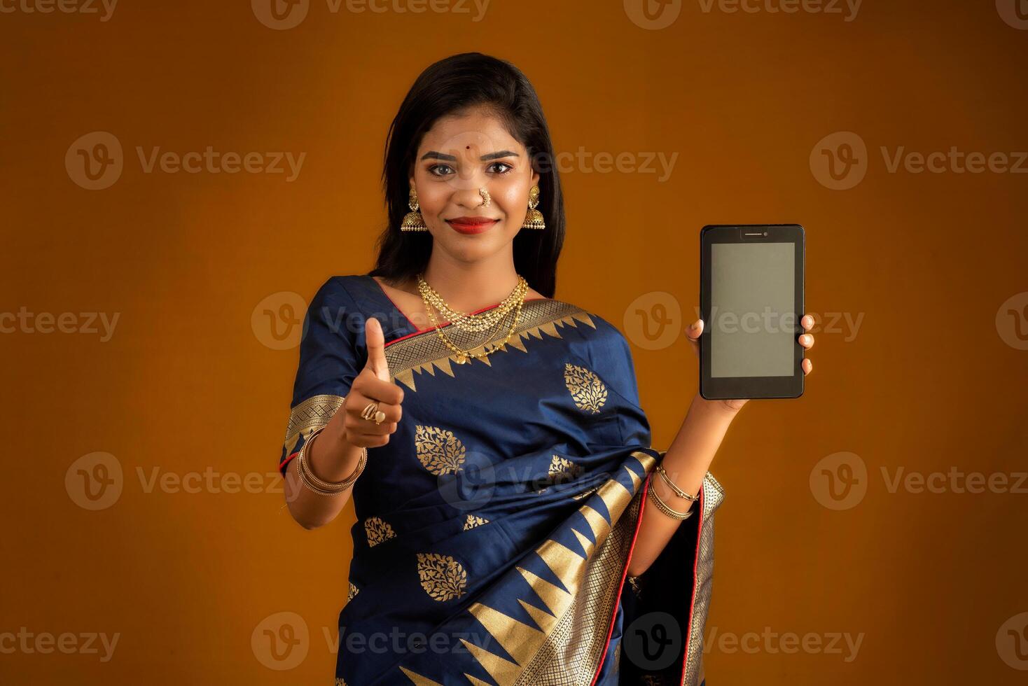 Young beautiful girl showing a blank screen of smartphone or mobile or tablet phone photo