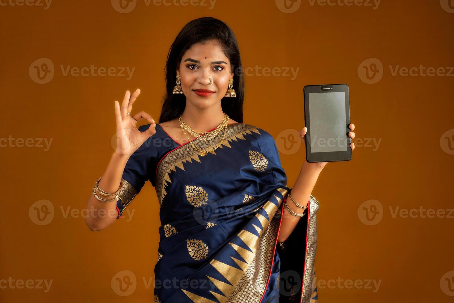 Young beautiful girl showing a blank screen of smartphone or mobile or tablet phone photo