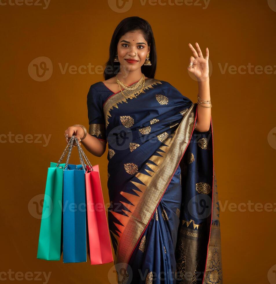 Beautiful Indian young girl or woman holding and posing with shopping bags on a brown background photo