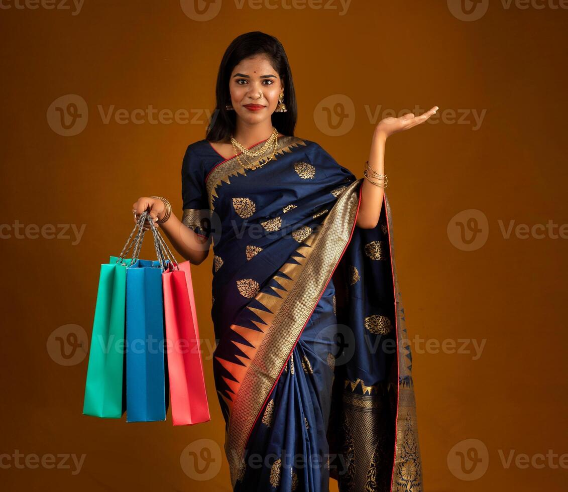 Beautiful Indian young girl or woman holding and posing with shopping bags on a brown background photo