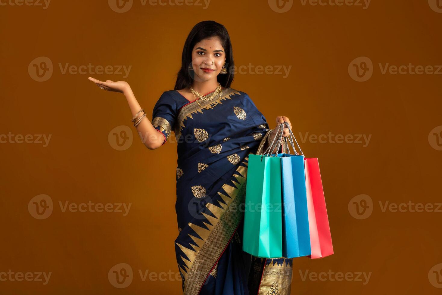 Beautiful Indian young girl or woman holding and posing with shopping bags on a brown background photo