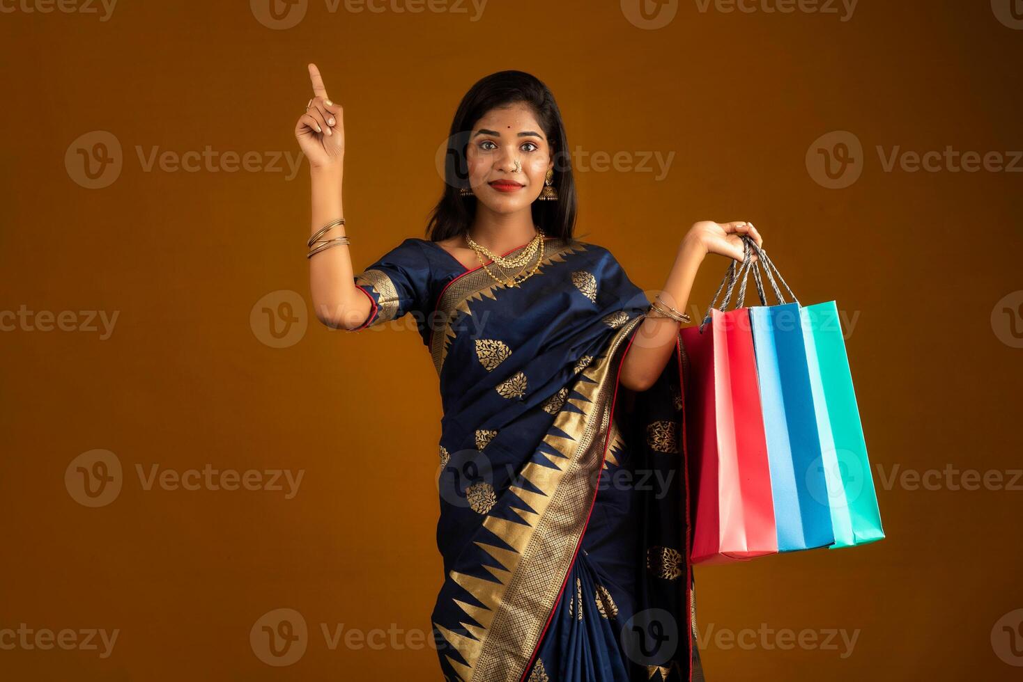 Beautiful Indian young girl or woman holding and posing with shopping bags on a brown background photo