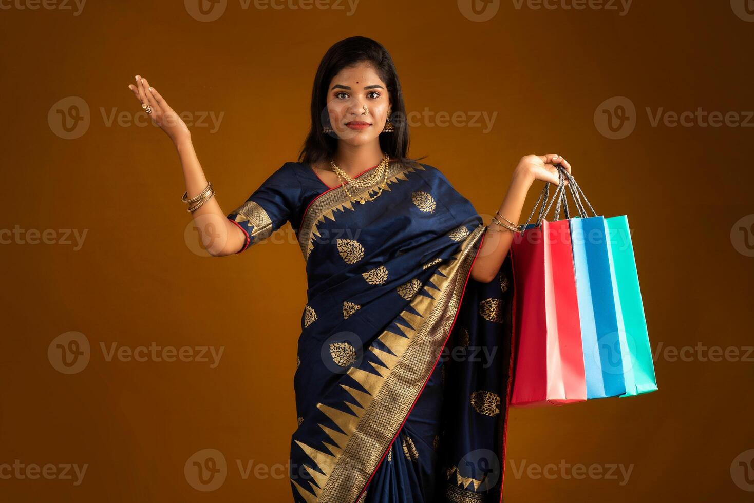 Beautiful Indian young girl or woman holding and posing with shopping bags on a brown background photo