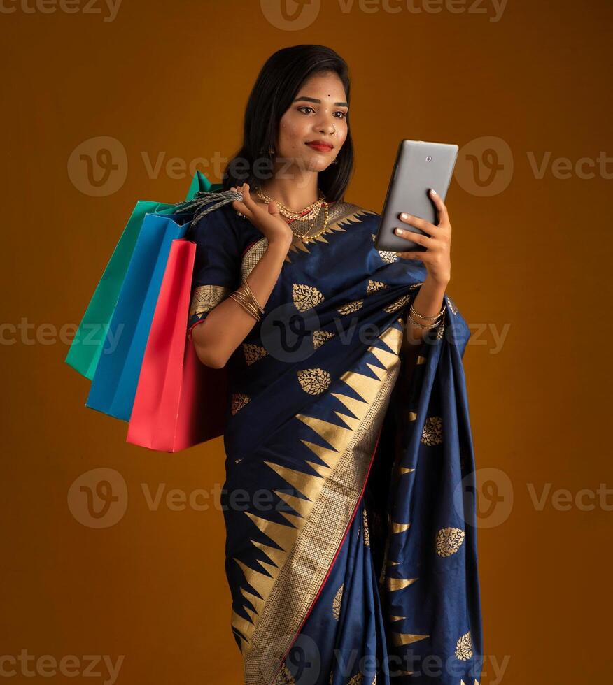 Portrait of a young woman with a mobile phone or tablet smartphone and shopping bags in her hands. photo