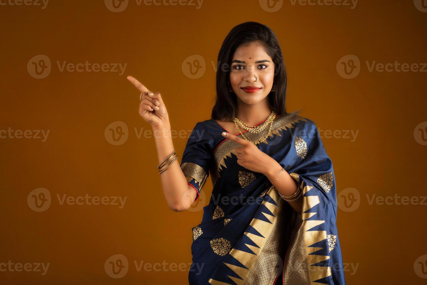Portrait of a cheerful young girl or woman pointing something with a happy smiling face. photo