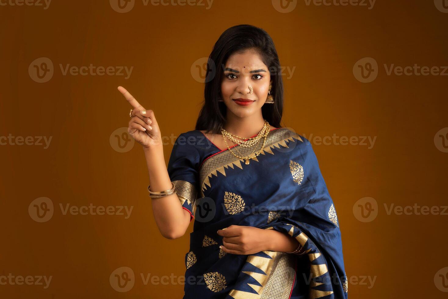 Portrait of a cheerful young girl or woman pointing something with a happy smiling face. photo