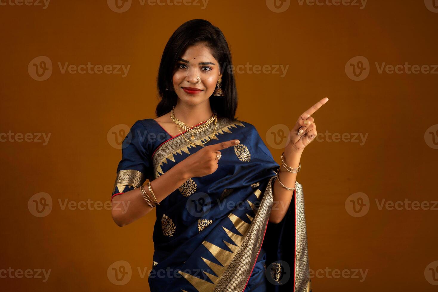 Portrait of a cheerful young girl or woman pointing something with a happy smiling face. photo
