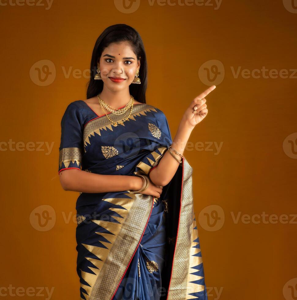 Portrait of a cheerful young girl or woman pointing something with a happy smiling face. photo