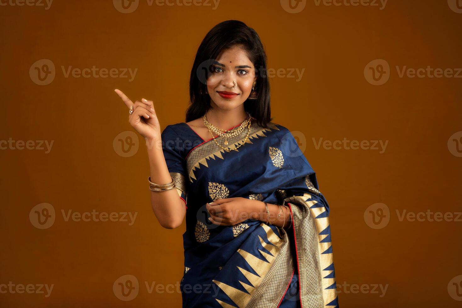 Portrait of a cheerful young girl or woman pointing something with a happy smiling face. photo