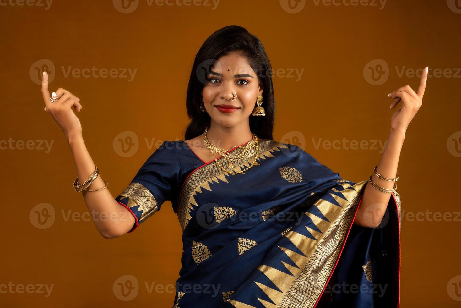 Portrait of a cheerful young girl or woman pointing something with a happy smiling face. photo