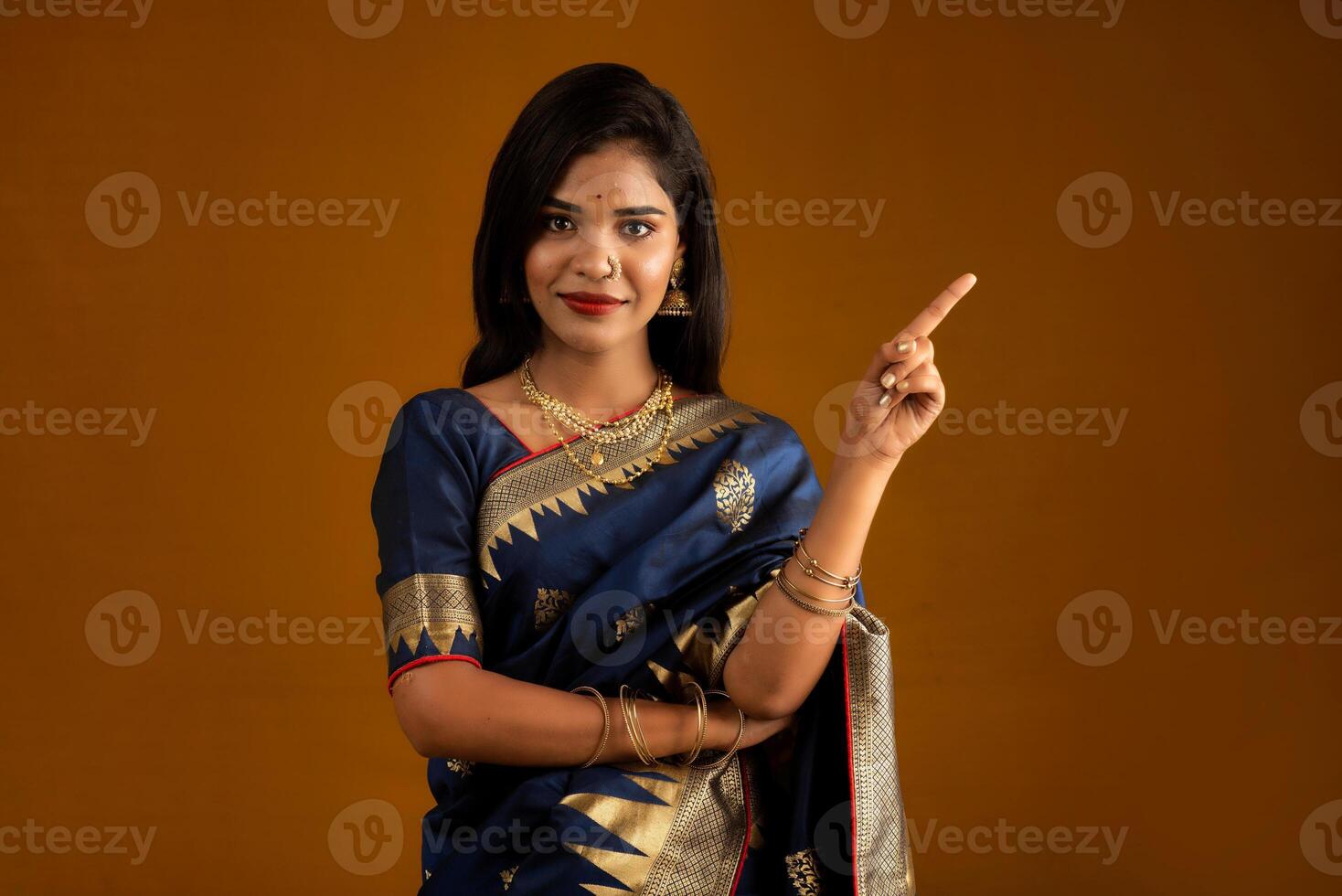 Portrait of a cheerful young girl or woman pointing something with a happy smiling face. photo