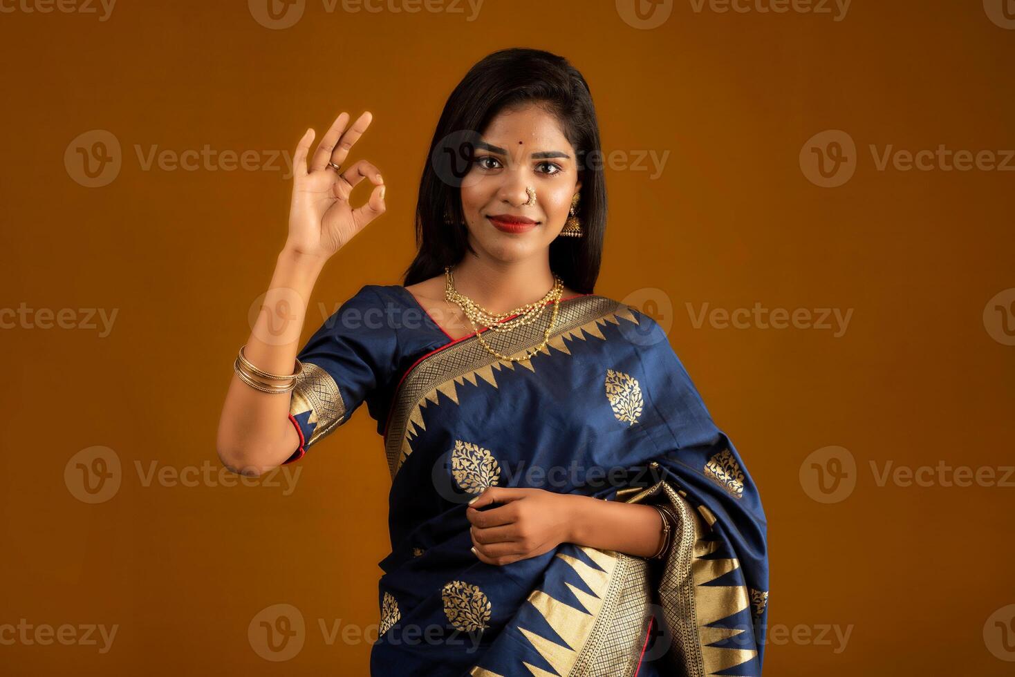 Young smiling girl showing ok sign on a brown background photo
