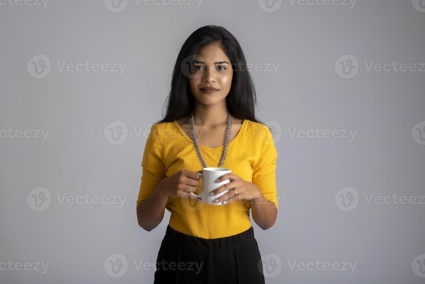 pretty young girl with a cup of tea or coffee posing on grey background photo