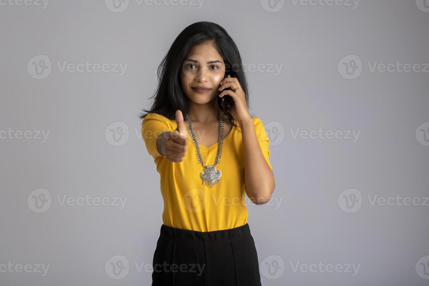 Young girl using mobile phone or smartphone on gray background photo