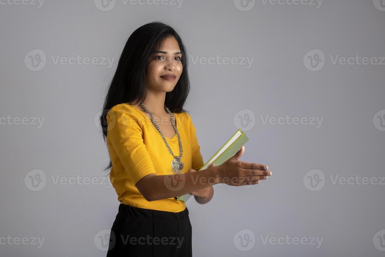 Pretty young girl posing with the book on grey background photo